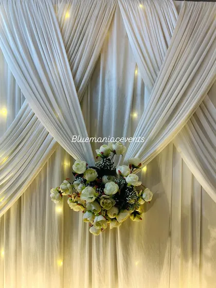 A detailed shot of the draped white backdrop with fairy lights. This highlights the texture of the fabric and the delicate floral bunch, details that add to the overall elegance of the design.