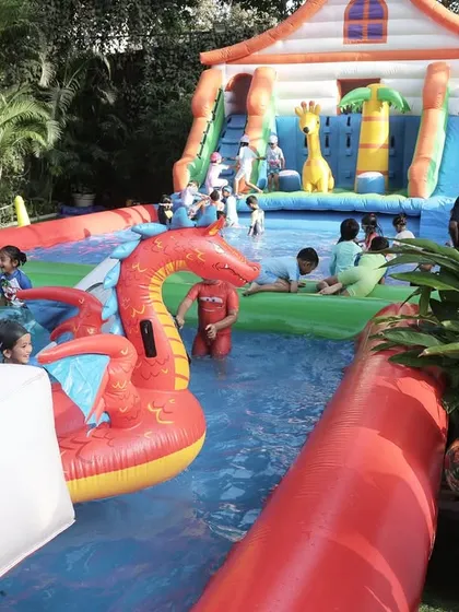A wide view of the inflatable pool setup, complete with a large slide and floating toys. I can transform any outdoor space into a mini water park.