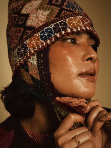 A close-up portrait highlighting a beautifully crafted winter hat from House of Wandering Silk. The focus is on the intricate details and the model's soft expression.