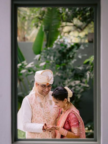 A sweet moment captured through a window frame. This creative composition adds depth and intimacy to the couple's wedding portrait.