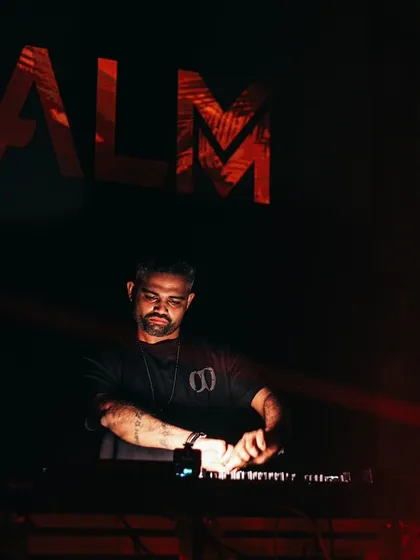 A low-lit, intense shot of me at the decks, with my logo glowing in the background.