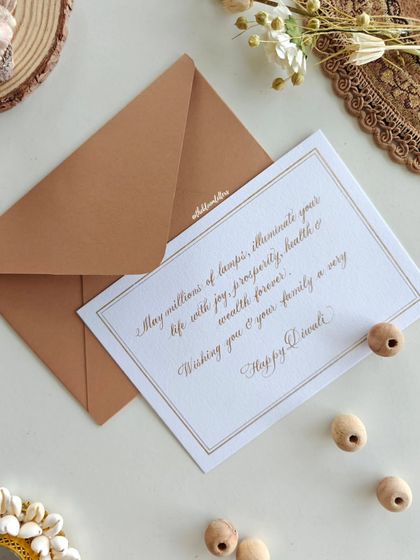 "May millions of lamps illuminate your life with joy, prosperity, health & wealth forever." A classic, elegant handwritten Diwali card with a simple border.