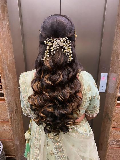 A reception hairstyle for a client with highlighted hair, featuring a half-updo with curls and a beautiful pearl and crystal accessory.