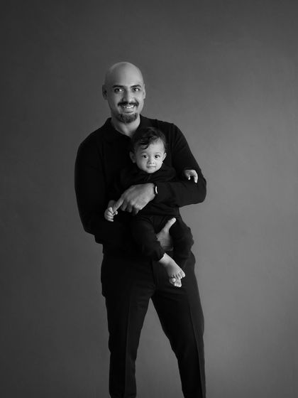 A strong and loving black and white portrait of a father holding his son. It's a classic pose that conveys a sense of protection and pride.