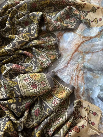 The Kalamkari silk dupatta is artfully draped to showcase its fluidity and the complexity of its hand-painted floral design. The off-white and green border adds a classic touch.