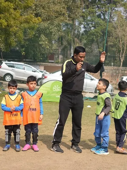 A coach lines up his young players, a mix of boys and girls, for instruction. This shows our focus on creating an inclusive and structured environment where every child's development is our top priority.
