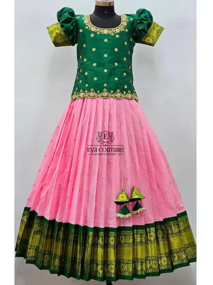 A classic mango-leaf green and pink Pattu Pavadai. The blouse has delicate butti work, and the skirt has a traditional contrast border.