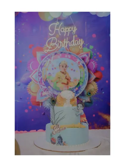 The custom-designed cake for the Krishna-themed birthday party, perfectly matching the backdrop and overall decor.