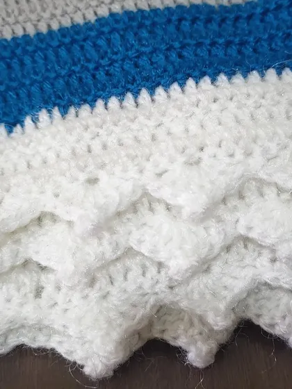 A close-up of the white crest pivot edging, which gives the shawl a delicate, scalloped border.