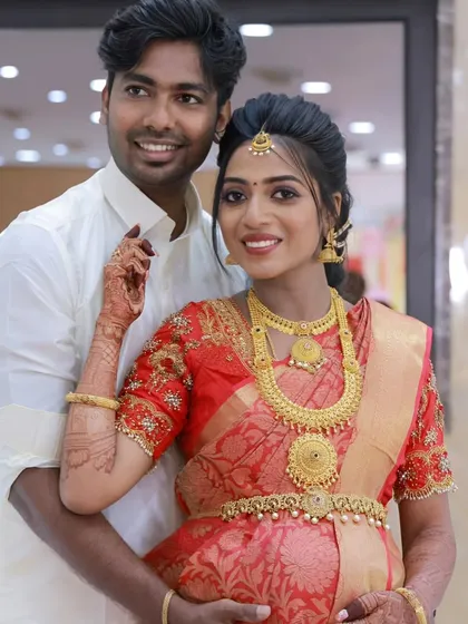 A happy couple at their baby shower. The mom-to-be is glowing in her red silk saree, with makeup that enhances her natural radiance.