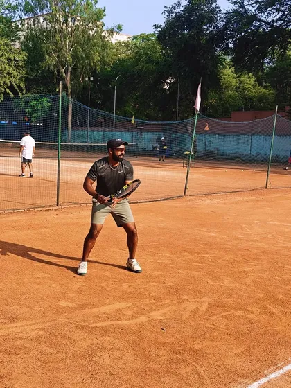 A coach demonstrating the ready position and split step on the clay court. We teach by doing, ensuring our players learn the correct fundamentals.