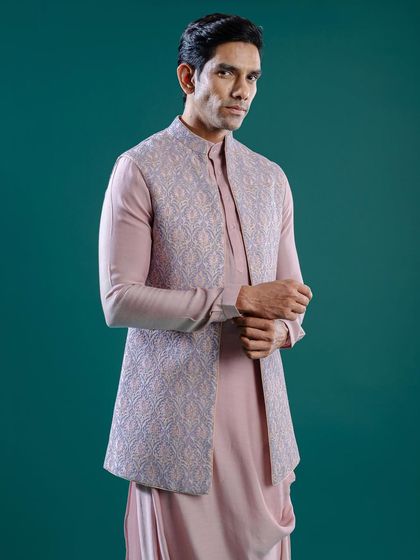 A cowl kurta in a soft pink is paired with a stunning Aari embroidery Jawahar jacket in a complementary lilac. This pristine and perfect outfit is ideal for daytime celebrations.