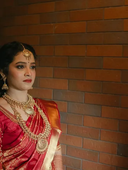 A profile view against a brick wall, creating a beautiful contrast. The makeup is flawless from every angle.