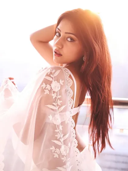 Actress Symrann K looking ethereal in a white embroidered saree against the sunset. This shot is a perfect blend of modern sensuality and traditional elegance.