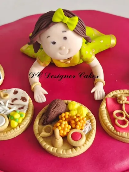 A close-up of the handcrafted fondant details on the Annaprashan cake. Each item is carefully sculpted to represent knowledge, wealth, and prosperity.