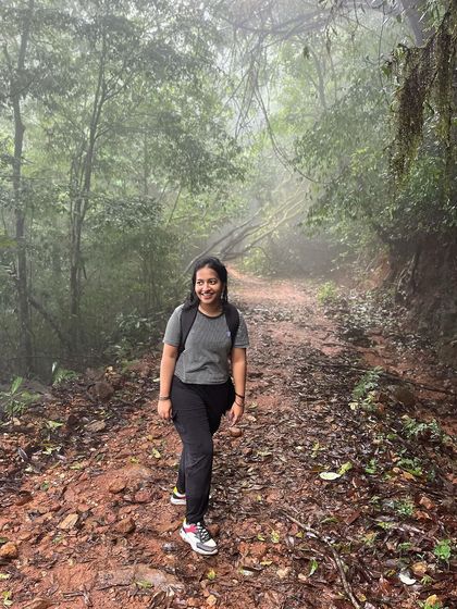 A trekker walking through a beautiful, misty forest path on the way to Kurinjal peak.