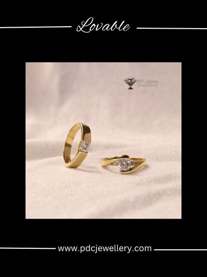 A lovable and elegant pair of solitaire rings for a couple. The gent's ring features a princess-cut diamond in a wide gold band, while the lady's ring has a delicate twist design, both showcasing a single, beautiful stone.