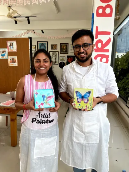 A couple with their finished miniature canvas paintings of a hummingbird and a butterfly. These small canvases are perfect for creating detailed and delicate artworks.