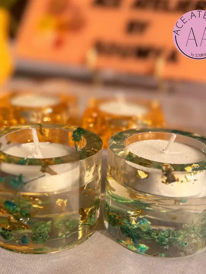 A set of round and square resin t-light holders. The clear resin showcases preserved green botanicals and gold flakes, bringing a touch of nature indoors.