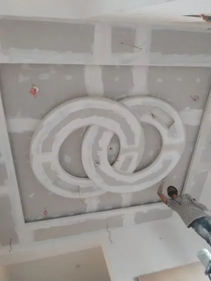 An intricate circular false ceiling design being crafted by skilled workers. I oversee this detailed POP work to ensure precision.