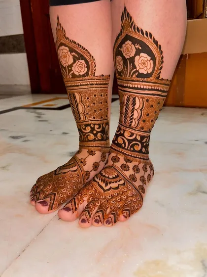 Bridal feet mehndi is essential for the complete look. This design features bold rose motifs on the legs, connected to intricate patterns covering the entire foot, ensuring every detail is perfect.