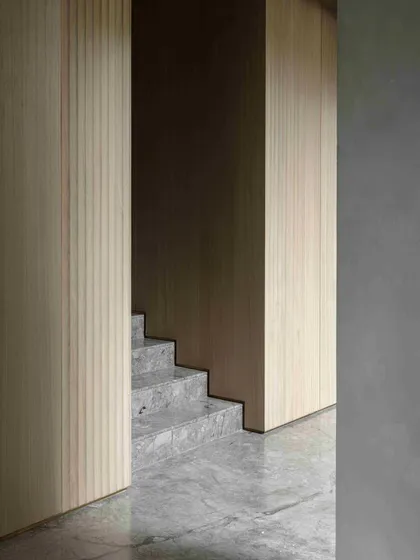 The clean transition from the marble staircase to the wooden fluted paneling at the Bammi Residence. This thoughtful detailing creates a harmonious flow between different materials and spaces.