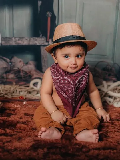 This little cowboy is sitting proudly next to his rocking horse, ready for his next adventure.