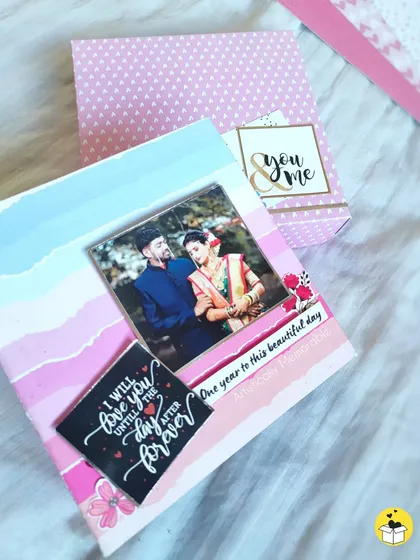 The cover of a pink and blue anniversary album, with a sweet quote and a photo of the couple.