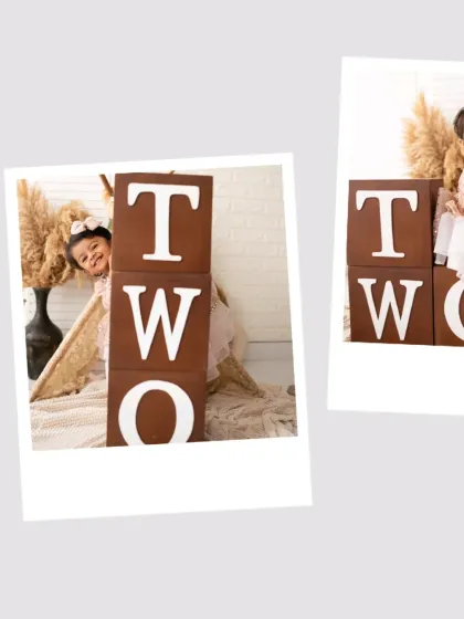 A little girl peeks out from behind "TWO" blocks during her second birthday shoot. We use props to create playful and interactive photos.