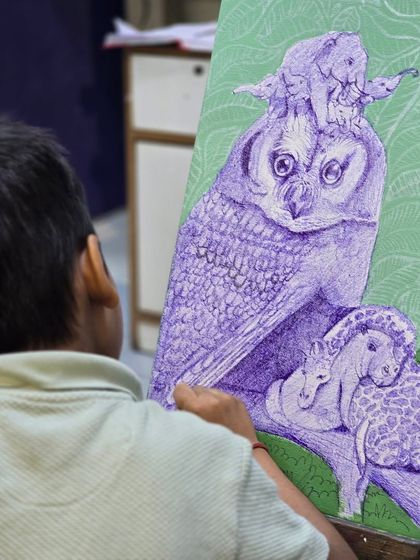 An over-the-shoulder view of a young boy working on his intricate ballpoint pen illustration, showcasing his steady hand and artistic vision.