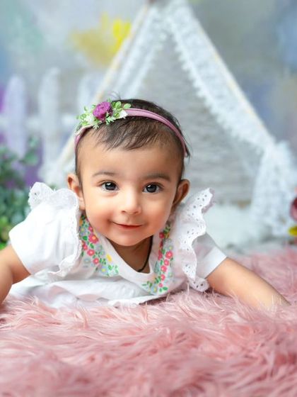 An innocent smile that melts my heart. This sweet baby girl is enjoying her tummy time during a milestone session on a soft pink rug.