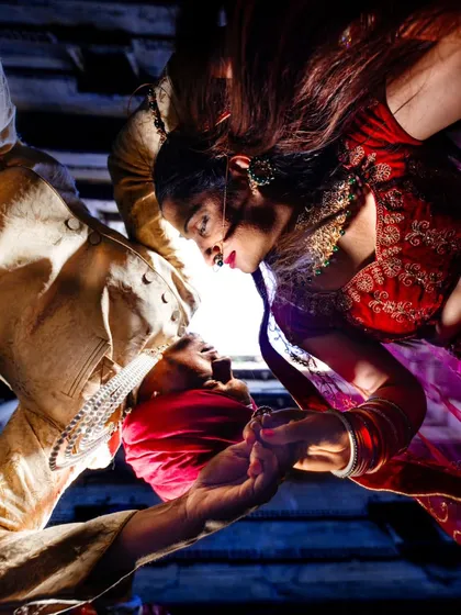 A creative, low-angle shot looking up at the couple through an opening in the stepwell. The unique perspective and dramatic lighting create an intimate and artistic portrait that feels otherworldly.