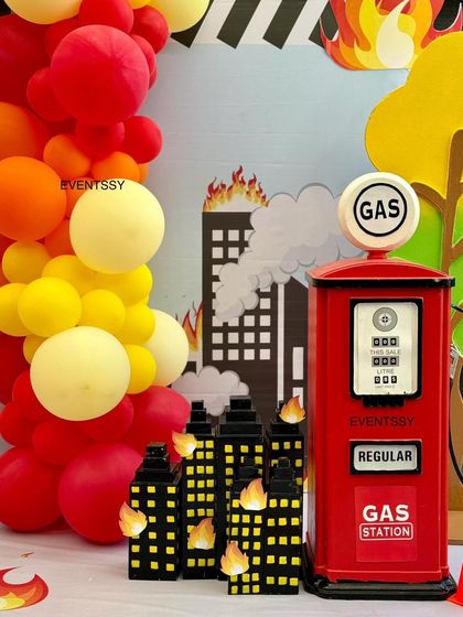 Themed props like a vintage gas pump and burning city buildings add detail and excitement to the firetruck party.
