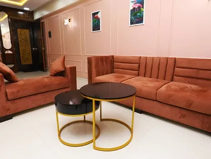 A living room designed with soft, blush tones and curved furniture for a gentle, calming aesthetic. The nested coffee tables add a touch of modern functionality.