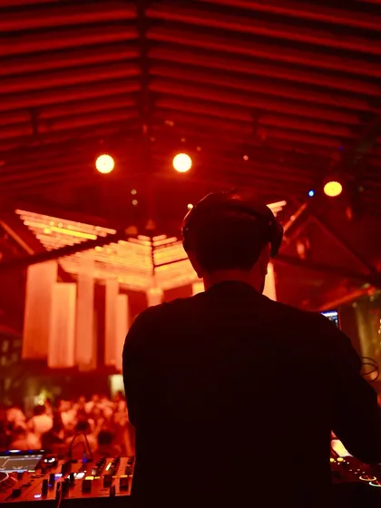A view from behind the decks at a club with a unique wooden ceiling and warm red lighting. I love performing in venues with distinct architecture and a great atmosphere.