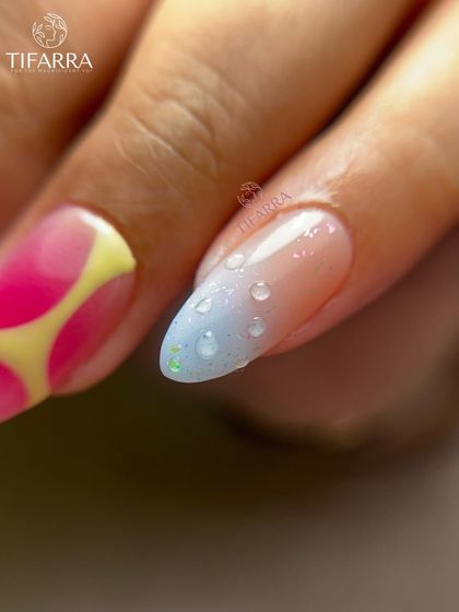 A detailed shot of a nail with a light blue ombre and realistic, 3D water droplets.