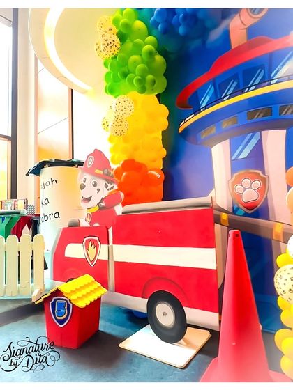 A detailed prop of Marshall in his fire truck, placed next to a recreation of the Paw Patrol lookout tower. These custom pieces are central to creating an immersive character-themed party.