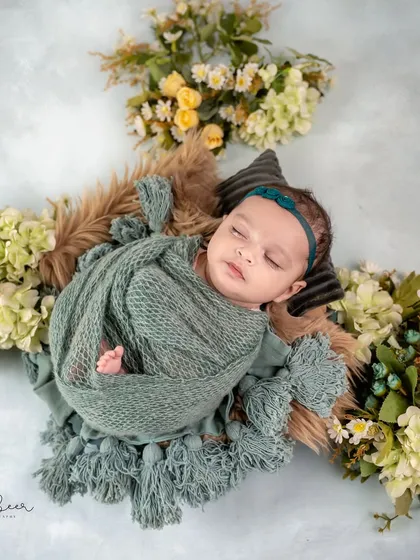 An overhead view of the baby nestled in a floral arrangement. The combination of green, yellow, and white flowers creates a fresh, natural feel for this infant photography session.