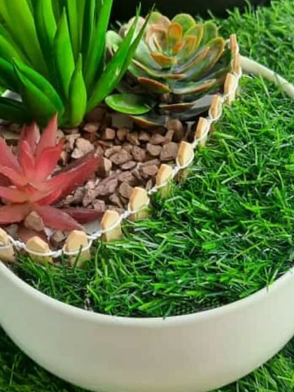 A beautiful artificial succulent Zen garden in a round white ceramic bowl. The different colours and textures of the succulents create a lovely, low-maintenance arrangement that makes a great gift.