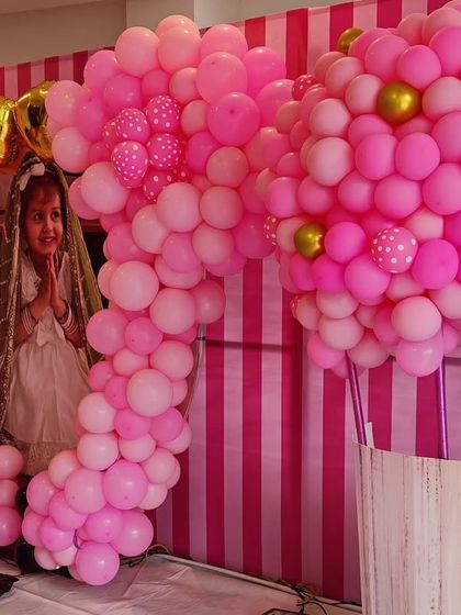 A close-up of a Minnie Mouse-themed party, showcasing the intricate pink balloon sculptures and a photo of the birthday girl.
