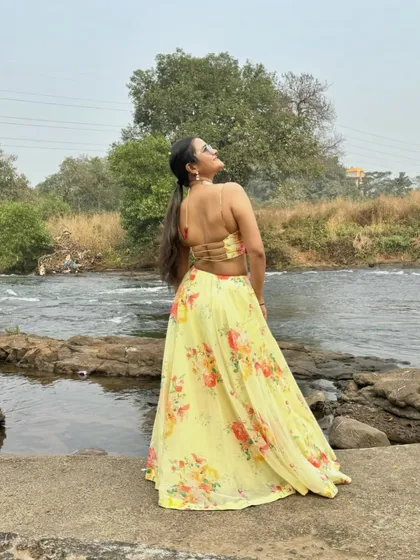 A back view of the floral lehenga, showcasing the strap details and my pose against the natural river backdrop.