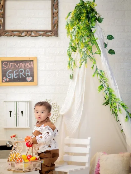 A one-year-old boy explores our cozy tent setup, playing with a basket of fruit. This shows the interactive and playful nature of our studio sessions.
