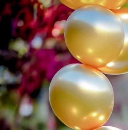 A close-up of shiny golden balloons against a colorful floral background. I capture the decor elements that contribute to the festive party atmosphere.