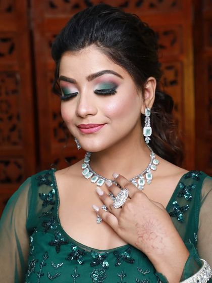 A close-up of a green-themed party look. The eyeshadow has beautiful shades of green and is paired with a nude lip.