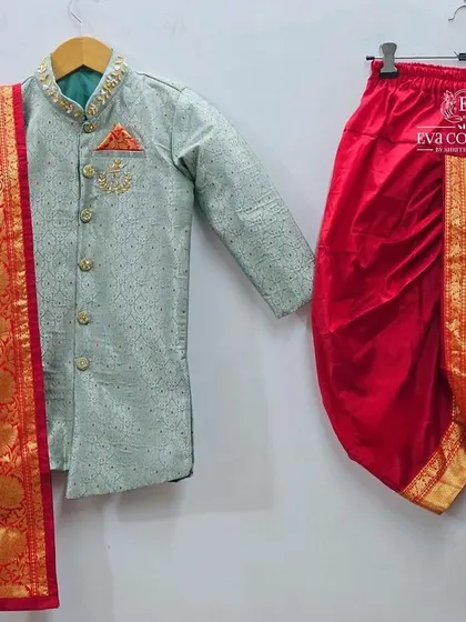 A sophisticated kurta set for a young boy. The light green brocade kurta is paired with a red dhoti and a matching red Banarasi scarf.