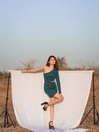 A full-length shot using a white backdrop in an outdoor setting. This creative setup makes the model and her green dress pop against the natural landscape.