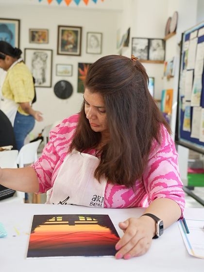 A participant works on her sunset painting, blending the colors to create a smooth gradient. The process is as enjoyable as the final result.
