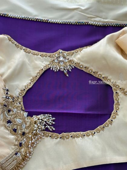 An off-white blouse with a keyhole back and peacock embroidery.