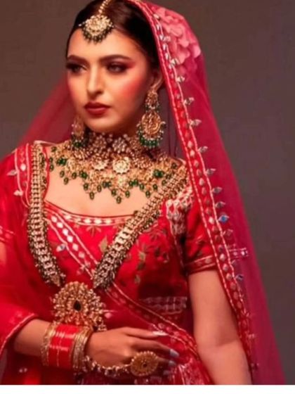 A bride in a red lehenga with a heavy, layered jewellery set. A classic and timeless look.