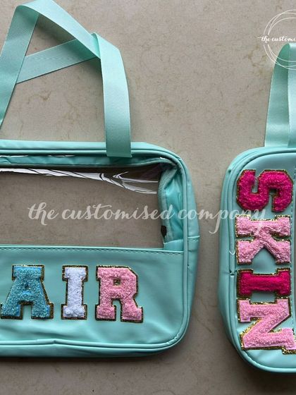 A pouch for every mood is just good planning. This set of clear, mint-colored pouches is customized with "HAIR" and "SKIN" in colorful patches, helping you keep your beauty products perfectly organized.